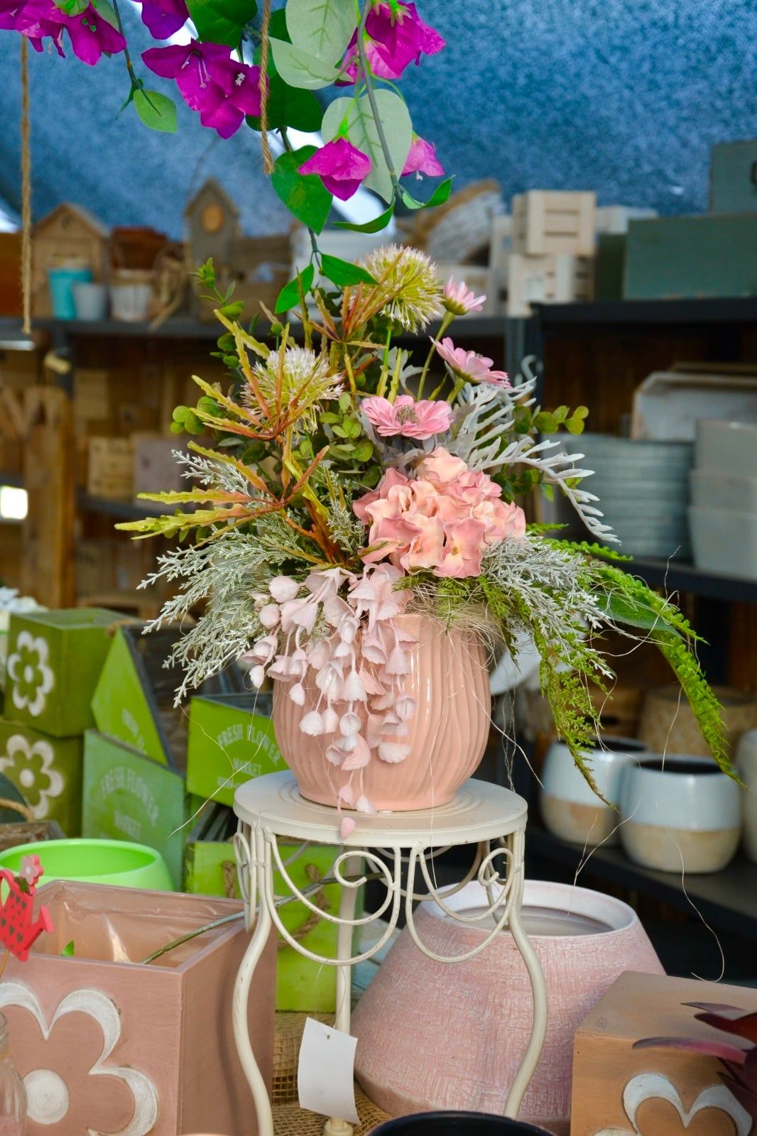 Vaso rosa in ceramica con una composizione di fiori artificiali, su un tavolino bianco
